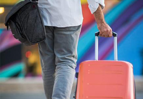 person pulling coral pink rolling suitcase