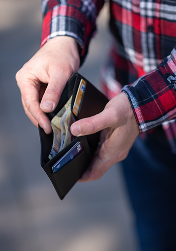 man holding open wallet with visa cards and cash showing