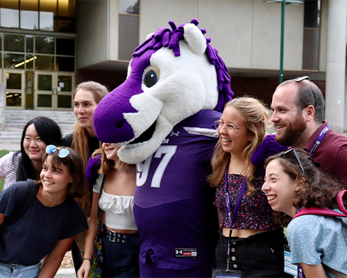 JW mascot standing with a group of international students smiling off-camera